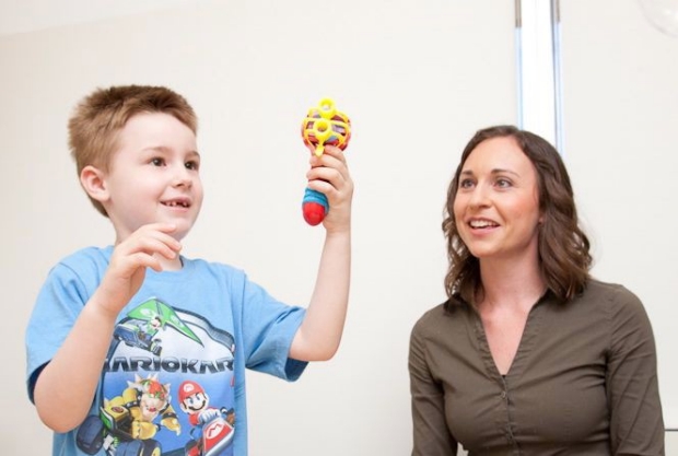 Dr. Casey Krueger and little boy holding up a noise making toy